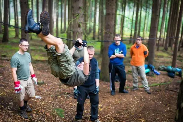 Mann überquert selbstgebaute Seilbrücke, während andere zuschauen
