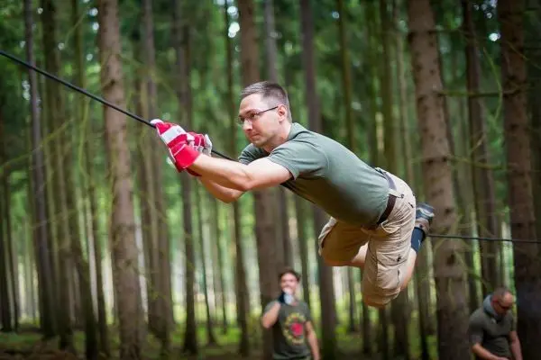 Mann überquert selbstgebaute Seilbrücke zwischen Bäumen im Wald