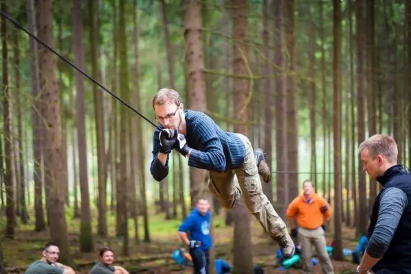 Mann überquert selbstgebaute Seilbrücke zwischen Bäumen im Wald