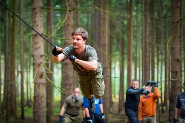 Mann überquert selbstgebaute Seilbrücke zwischen Bäumen im Wald