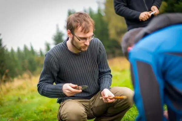 Messer bearbeitet Holzstück auf dem Boden in einer natürlichen Umgebung
