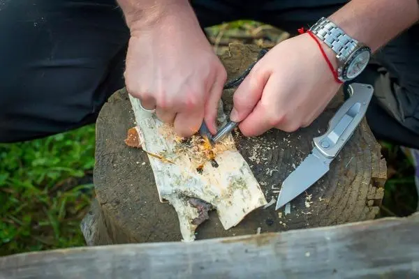 Messer schabt Rinde von einem Holzstück auf einem Baumstumpf