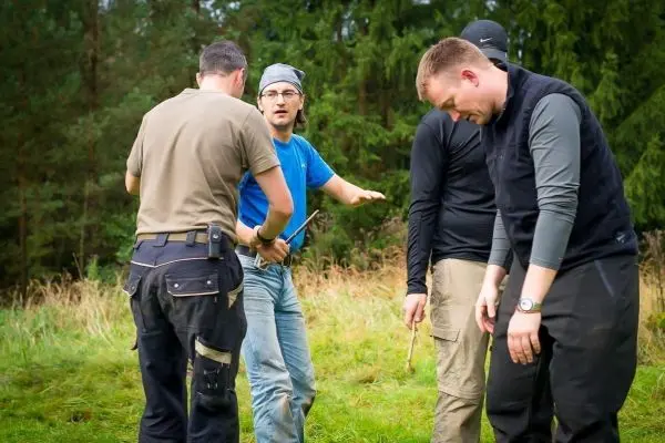 Person zeigt anderen Personen den Umgang mit einem Stock beim Training