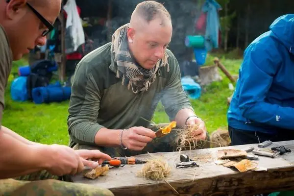 Person zündet mit einem Feuerzeug Zunder auf einem Tisch an