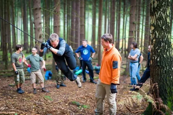 Selbstgebaute Seilquerung wird von einer Person überquert, während andere zuschauen