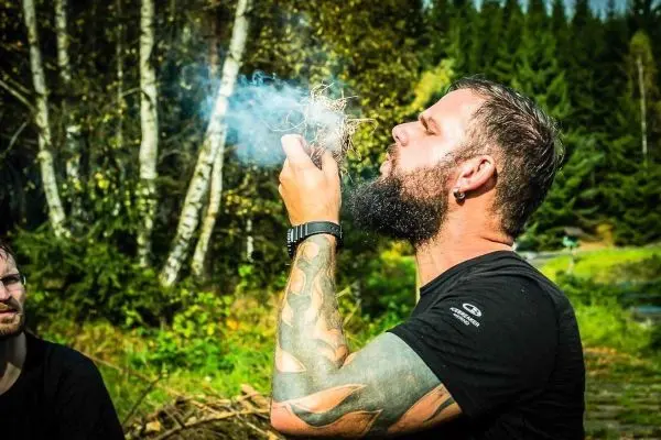 Zunder glimmt in Händen, Rauch steigt auf