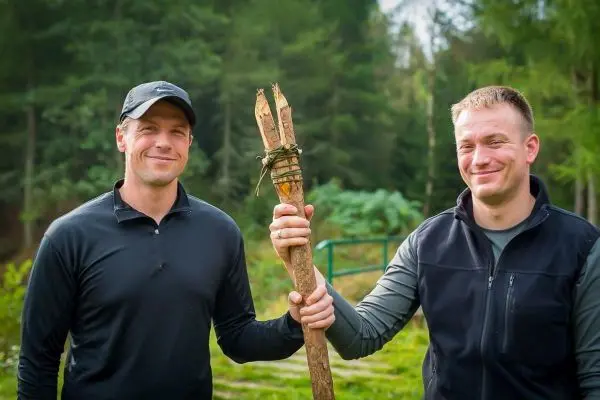 Zwei Männer halten gemeinsam einen selbstgebauten Speer aus Holz