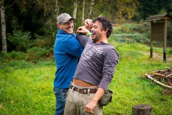 Zwei Männer lachen und interagieren in einer grünen Umgebung