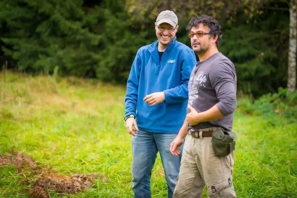 Zwei Männer stehen in einer Wiese und unterhalten sich