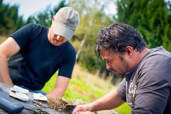 Zwei Personen arbeiten an einem Tisch mit Materialien im Freien
