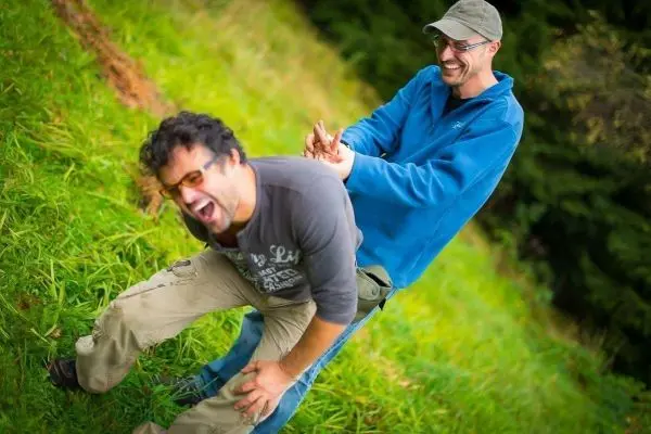Zwei Personen stehen auf einer Wiese und lachen miteinander