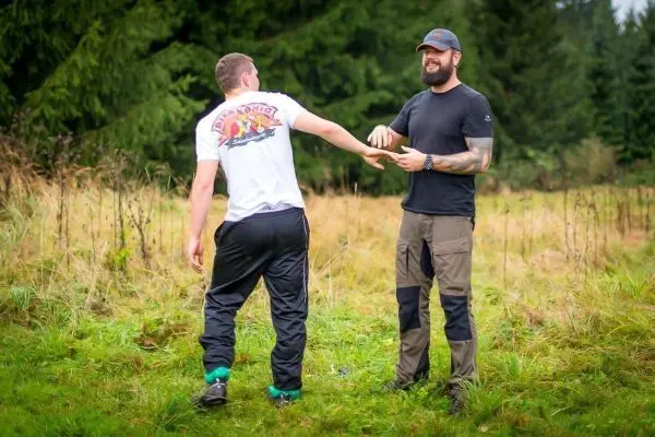Zwei Personen stehen in einer Wiese und interagieren miteinander