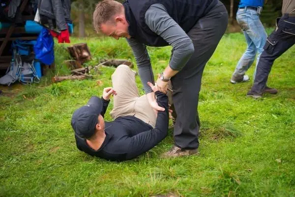 Zwei Personen üben eine Bodenkampftechnik auf einer Wiese aus