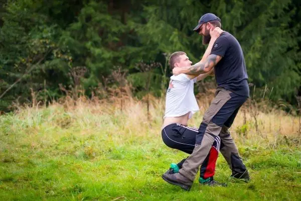 Zwei Personen üben eine körperliche Technik im Freien auf einer Wiese