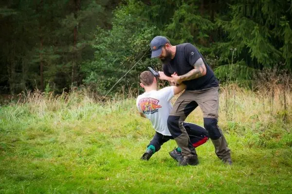 Zwei Personen üben eine Selbstverteidigungstechnik auf einer Wiese