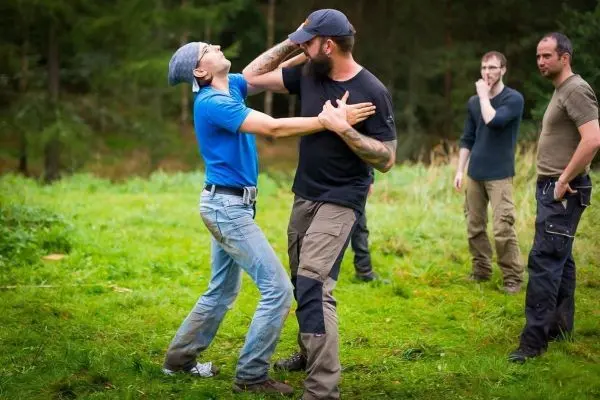 Zwei Personen üben eine Selbstverteidigungstechnik auf einer Wiese