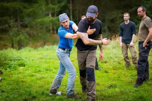 Zwei Personen üben eine Selbstverteidigungstechnik auf einer Wiese