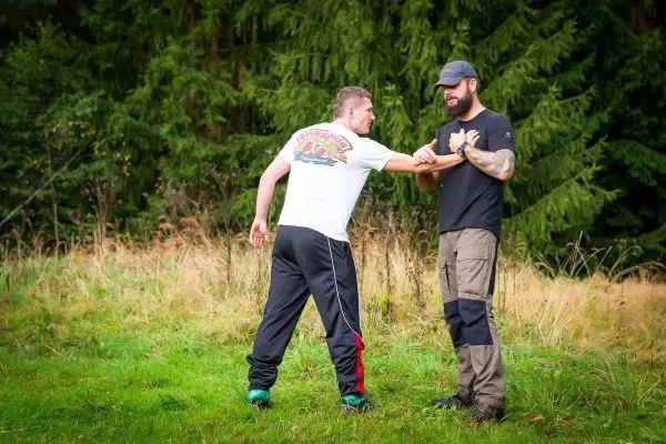 Zwei Personen üben eine Selbstverteidigungstechnik im Freien