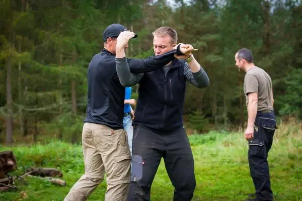 Zwei Personen üben eine Selbstverteidigungstechnik im Freien