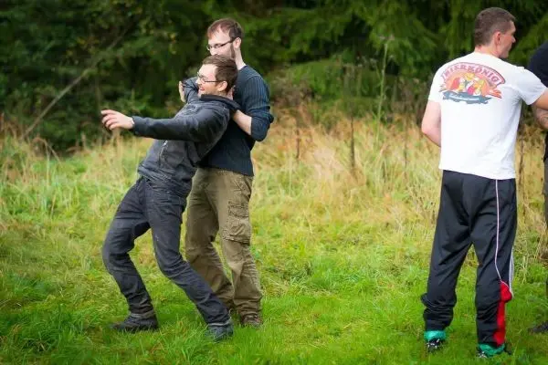 Zwei Personen üben eine Selbstverteidigungstechnik im Gras