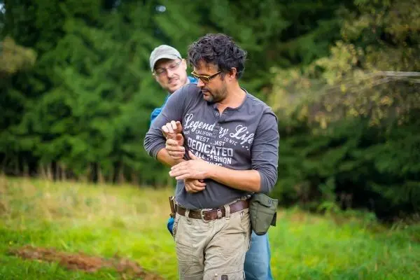 Zwei Personen üben eine Technik zur Handentwaffnung im Freien
