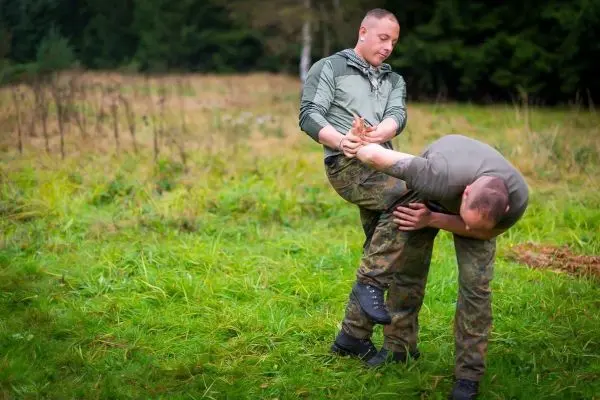 Zwei Personen üben eine Technik zur Kontrolle des Gegners im Gras