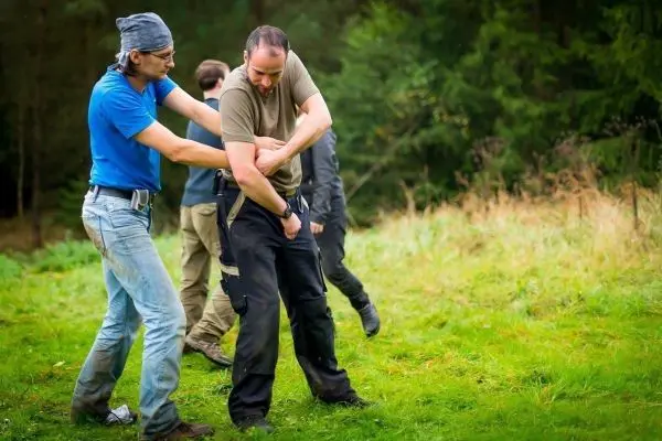 Zwei Personen üben eine Technik zur Kontrolle in einer grünen Wiese