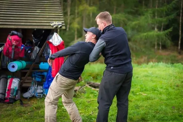 Zwei Personen üben eine Technik zur Selbstverteidigung im Freien