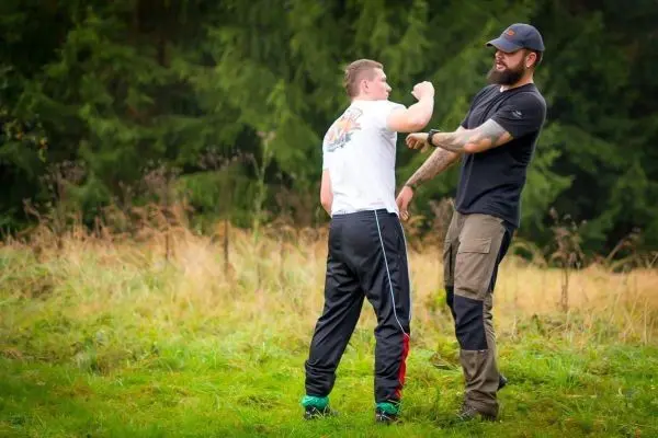 Zwei Personen üben eine Technik zur Selbstverteidigung im Freien