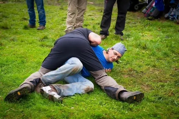 Zwei Personen üben einen Bodenkampf auf einer Wiese
