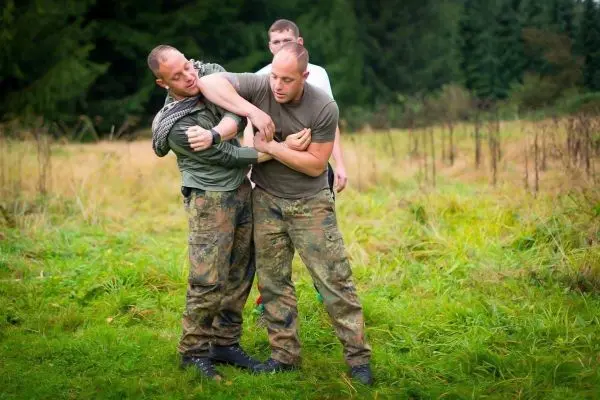 Zwei Personen üben einen Nahkampfgriff auf einer Wiese aus
