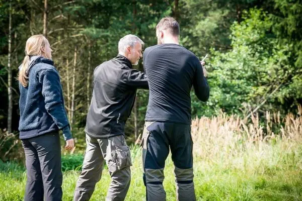 Drei Personen stehen im Freien und diskutieren eine Technik oder Methode