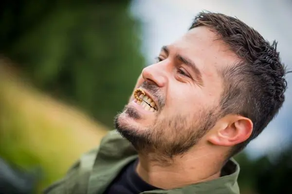 Ein Mann lächelt mit sichtbaren Zähnen in der Natur