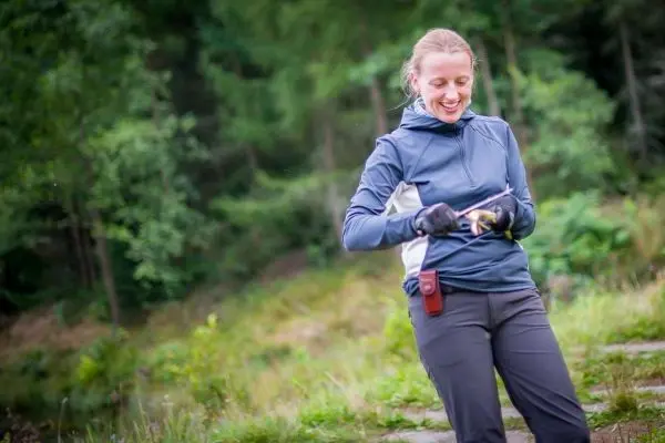 Frau bearbeitet ein Stück Holz mit einem Messer im Freien