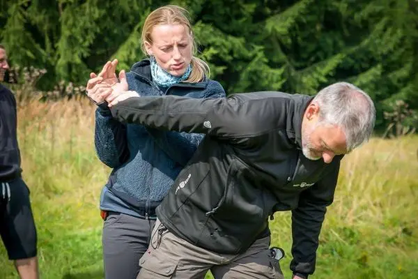 Frau übt eine Selbstverteidigungstechnik an einem Mann im Freien