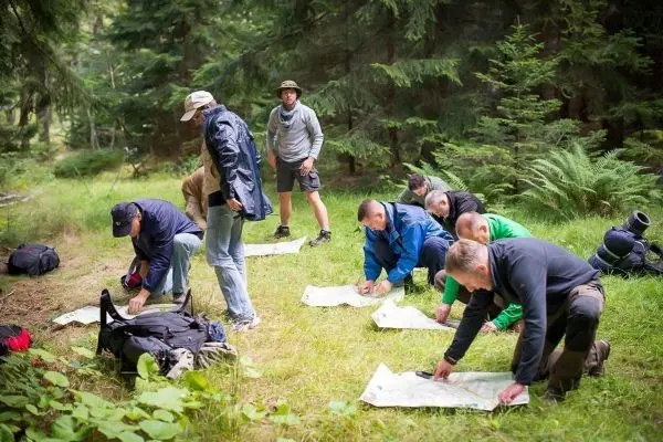 Gruppe von Personen studiert Karten im Wald beim Überlebenstraining