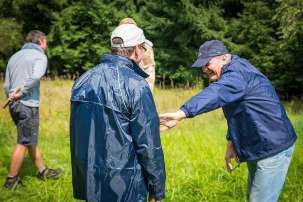 Gruppendiskussion im Freien, Teilnehmer tragen Regenjacken und lachen
