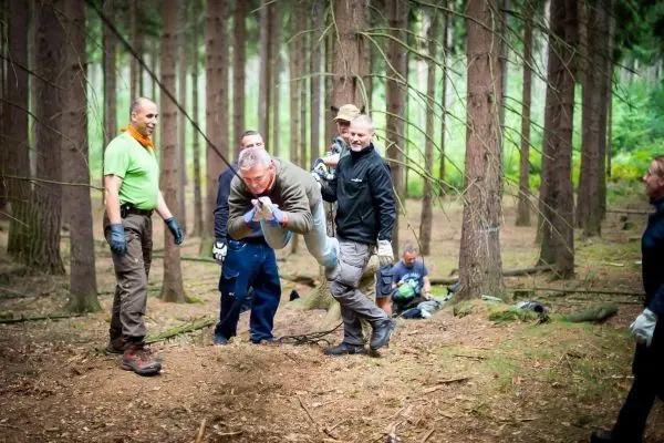Gruppenteilnehmer überqueren eine selbstgebaute Seilbrücke im Wald