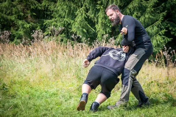 Kämpfer hält Gegner am Arm und zieht ihn nach unten auf den Boden