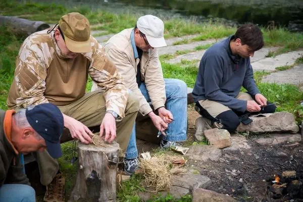 Männer bereiten Zunder und Feuermaterial am Bodenfeuer vor