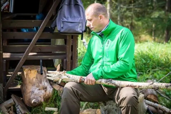 Mann bearbeitet einen Holzstock auf einem Baumstumpf