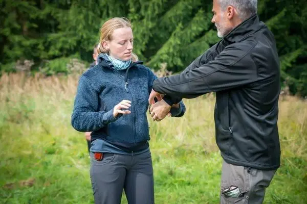 Mann demonstriert eine Technik an der Hand einer Frau im Freien