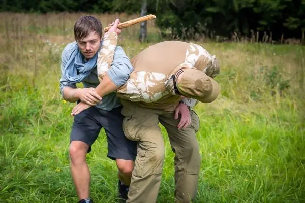 Mann führt einen Hebelgriff mit einem Stock gegen einen anderen Mann aus