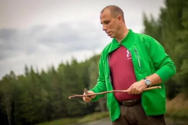 Mann hält einen Stock in der Hand und bearbeitet ihn mit einem Messer