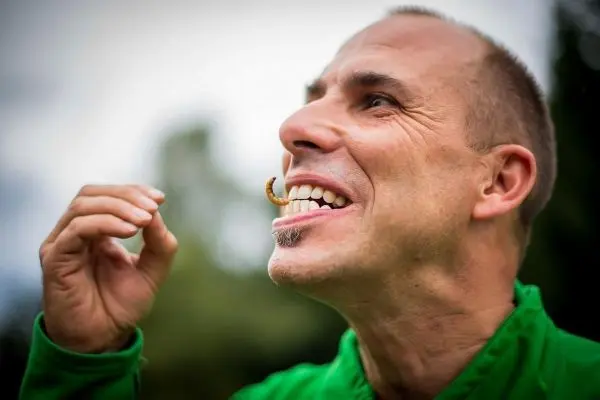 Mann hält einen Wurm zwischen den Zähnen und lächelt