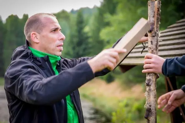 Mann hält Holzstück und bearbeitet es mit einer Klappsäge