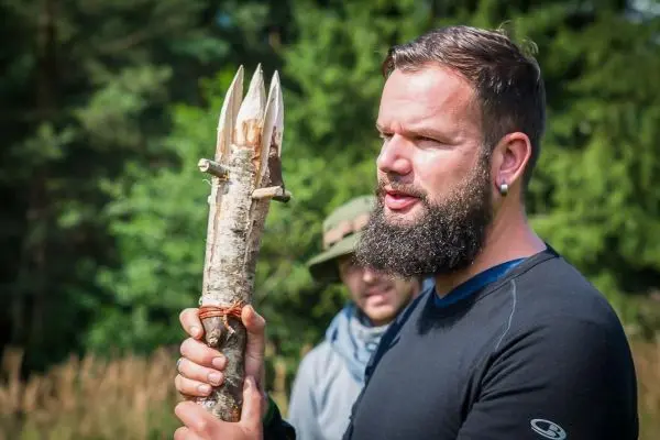 Mann hält selbstgebaute Speerspitze aus Holz in der Hand