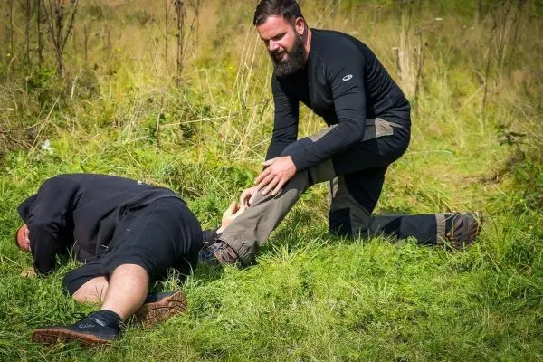 Mann leistet Erste Hilfe bei verletzter Person im Gras