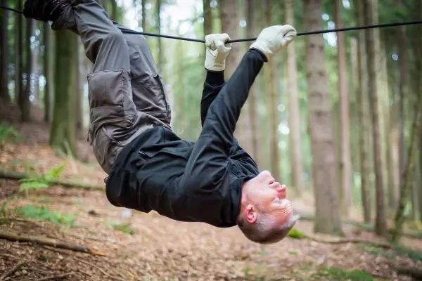 Mann überquert selbstgebaute Seilbrücke in einem Waldgebiet