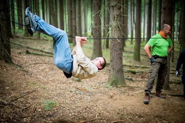Mann überquert selbstgebaute Seilbrücke zwischen Bäumen im Wald